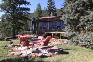 Beautiful cabin in the woods with red deck chairs in front