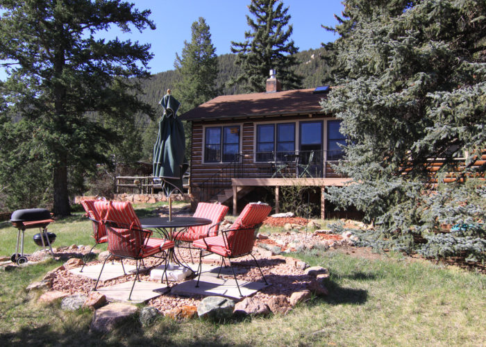 Beautiful cabin in the woods with red deck chairs in front